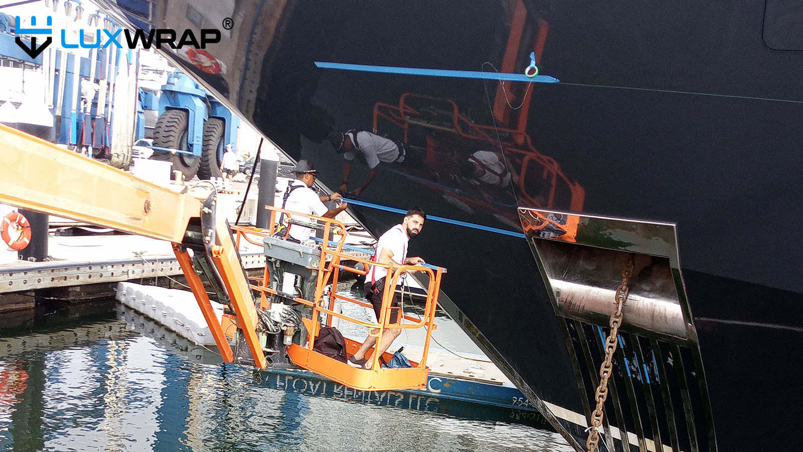 Large superyacht bow wrapped with access from cherry pickers.