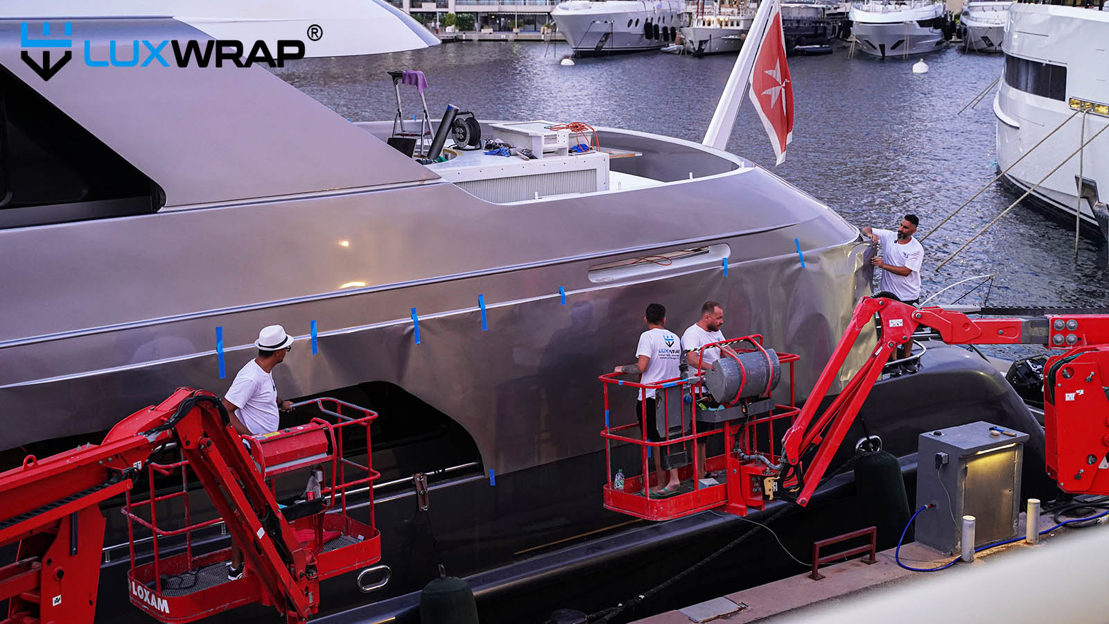 Cherry picker access to wrap exterior parts of superyacht superstructure in silver.